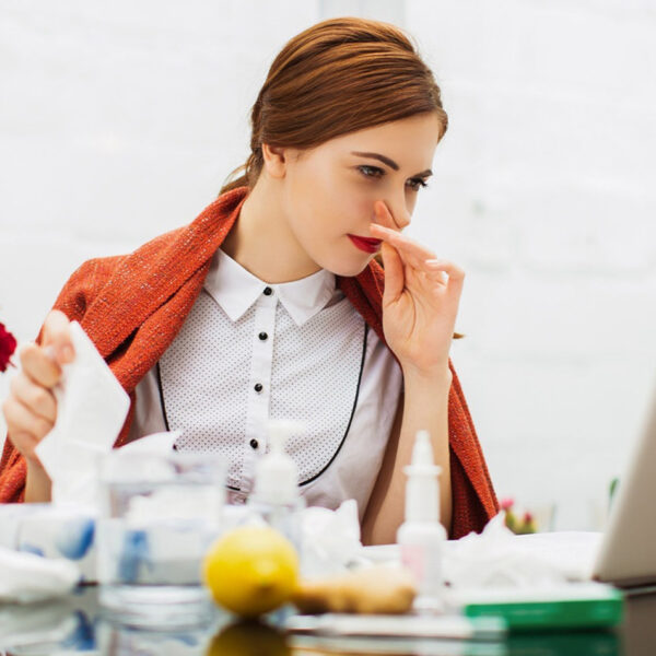 Külmetushaigusega naine kontoris.